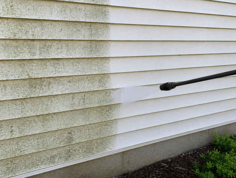 pressure washer cleaning dirty house siding with visible before and after difference